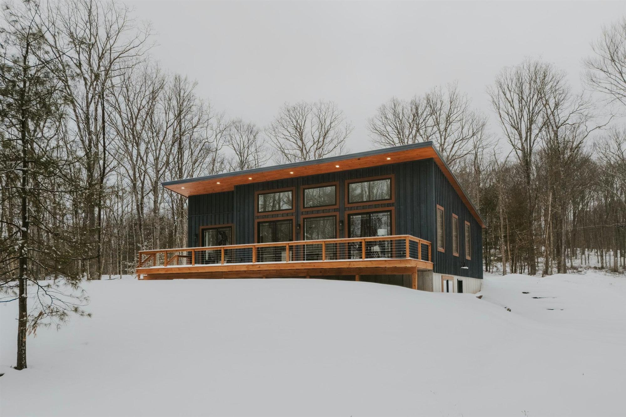 A modern home with a wooden deck in a snowy landscape