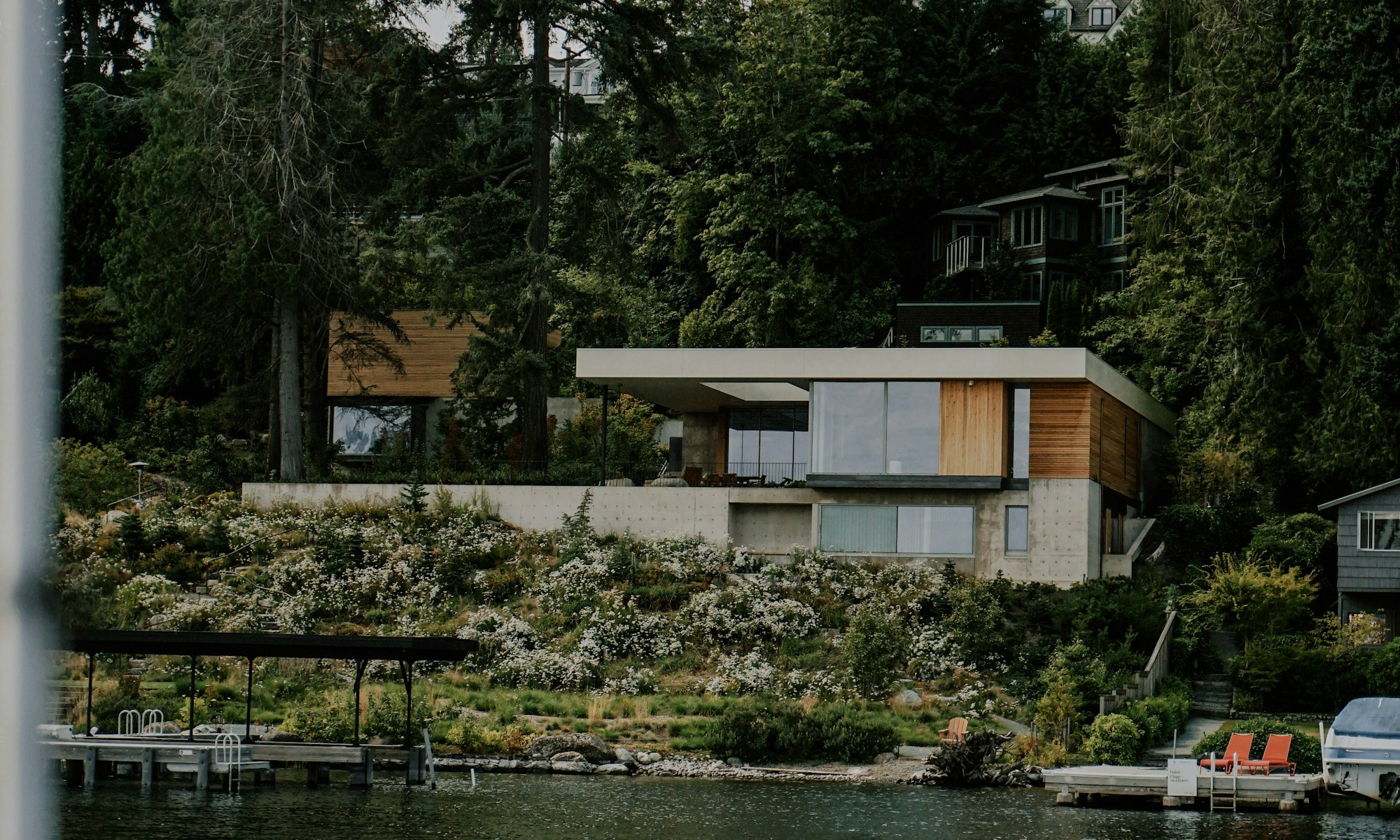 A modern home set among tall trees at the edge of a lake