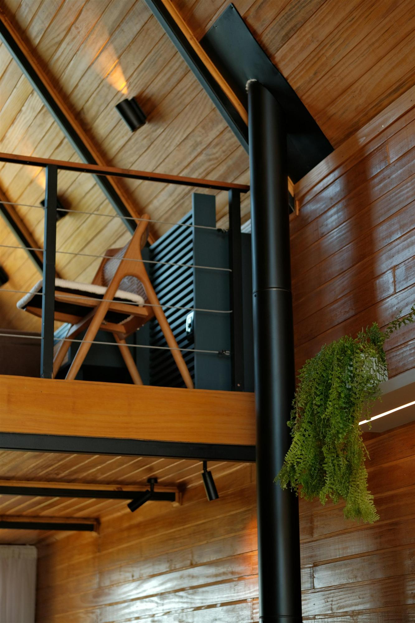 A living room with warm wood walls and a mezzanine above
